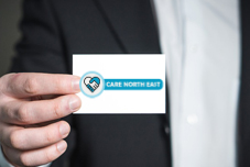 Image of a businessman holding a Care North East business card.